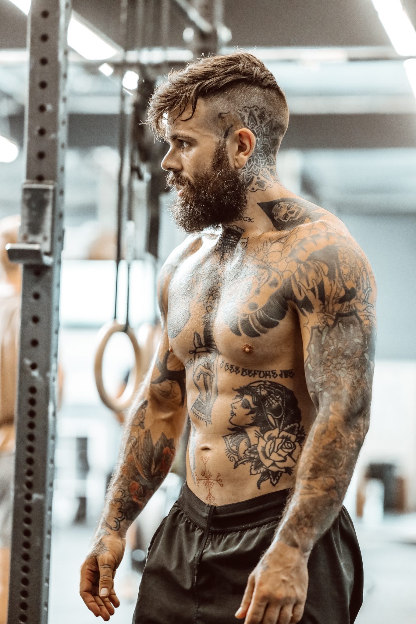 Scott Britton, shirtless in a gym, looking down at the bar