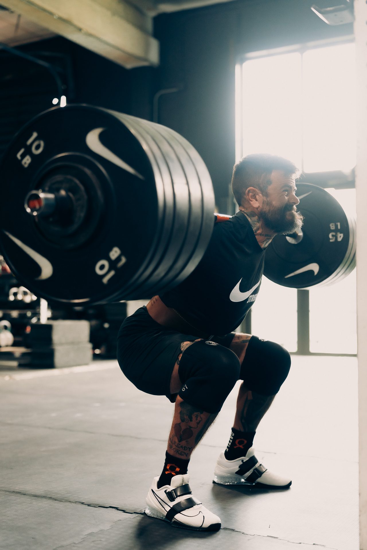 Scott Britton back squatting a loaded barbell